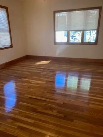a view of empty room with window and wooden floor