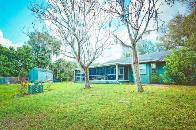 a view of a house with a yard and large trees