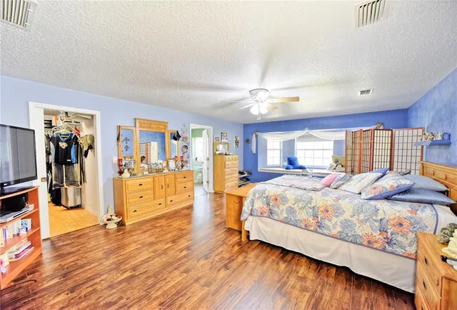 a spacious bedroom with a bed and wooden floor