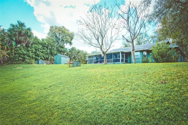 a view of a house with a big yard and large trees