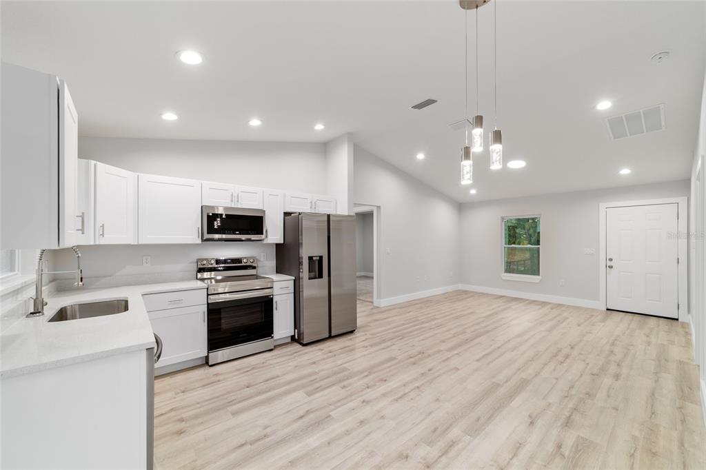 15776 Southwest 27th Lane Ocala, FL 34481 - Photo 21 of 39 a view of kitchen with stainless steel appliances granite countertop a sink a stove a refrigerator and a oven with wooden floor