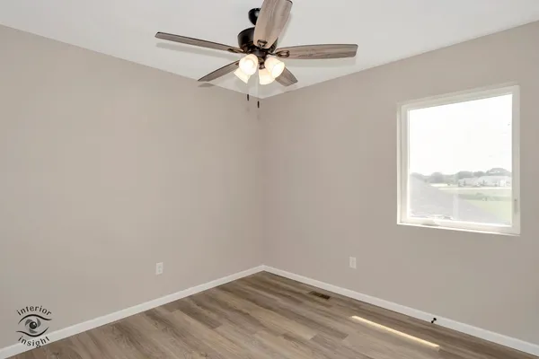 an empty room with a window and a fan
