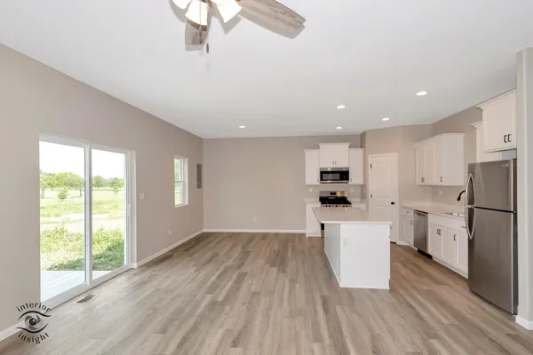 a view of kitchen with stainless steel appliances refrigerator stove and wooden floor