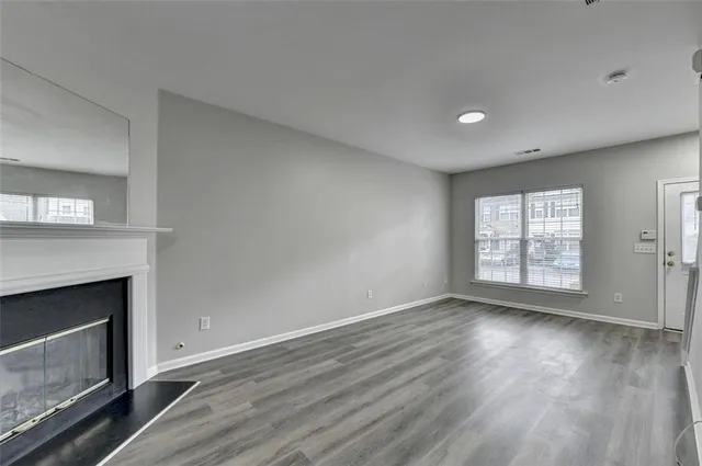 a view of an empty room with wooden floor fireplace and a window