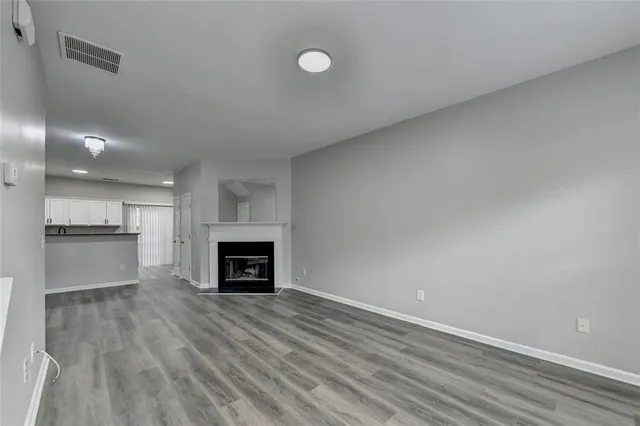 an empty room with wooden floor fireplace and windows