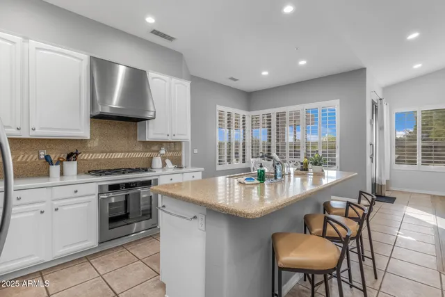 a dining hall with stainless steel appliances granite countertop a stove a sink a dining table and chairs