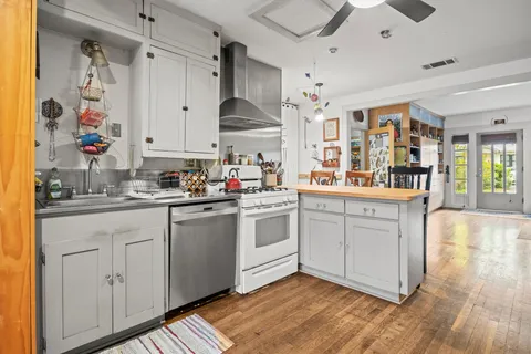 a kitchen with stainless steel appliances white cabinets and wooden floor