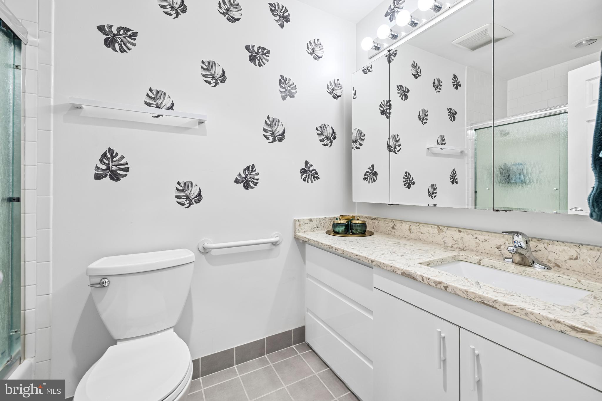 2515 Boston Street, Unit 1206 Baltimore, MD 21224 - Photo 24 of 29 a bathroom with a granite countertop toilet sink and mirror