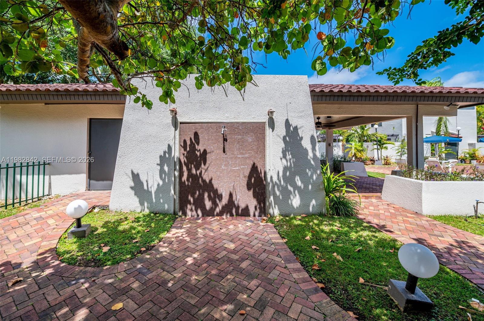 4702 Southwest 67th Avenue, Unit O7 Miami, FL 33155 - Photo 31 of 32 a front view of a house with a yard fountain and a lawn chair