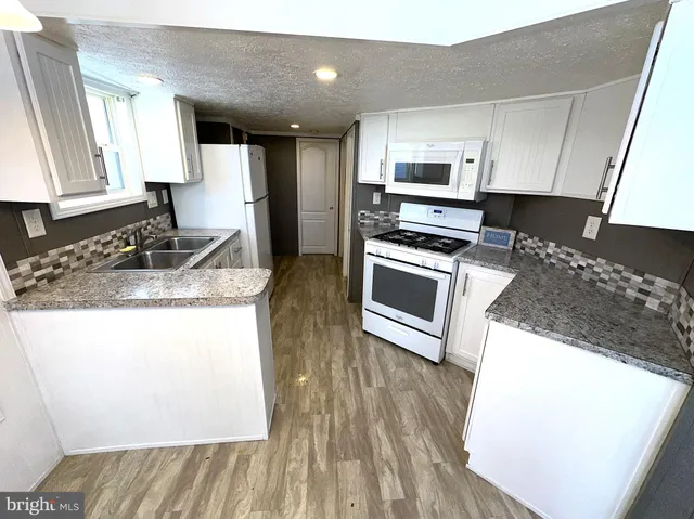 a kitchen with granite countertop a sink cabinets and stainless steel appliances