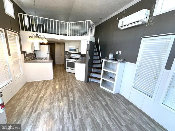 a view of a hallway with wooden floor windows and a kitchen view