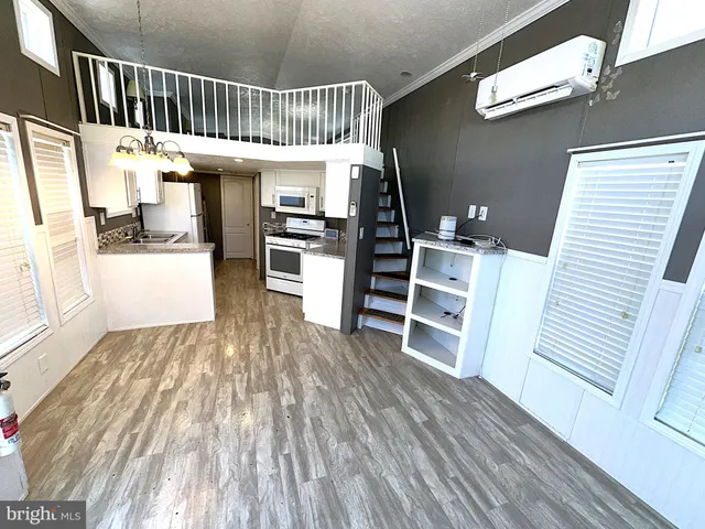a view of a hallway with wooden floor windows and a kitchen view