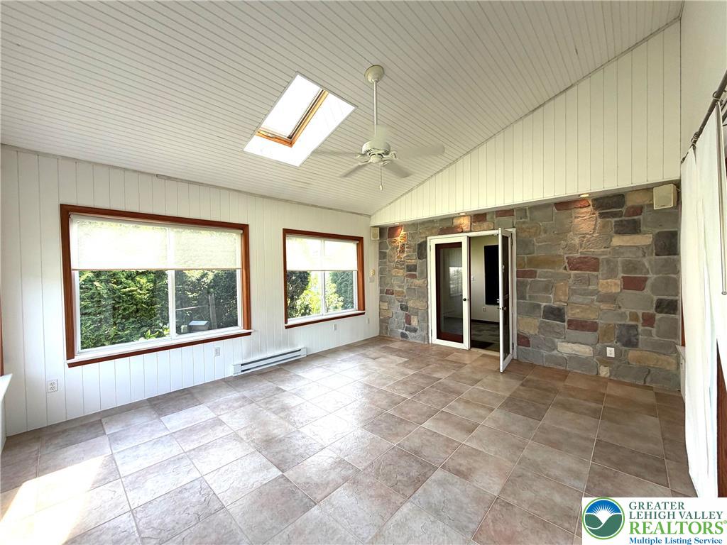 2741 Limestone Street Coplay, PA 18037 - Photo 20 of 35 A skylight and large windows illuminate this versatile bonus room, showcasing its stone accent wall and tile flooring.
