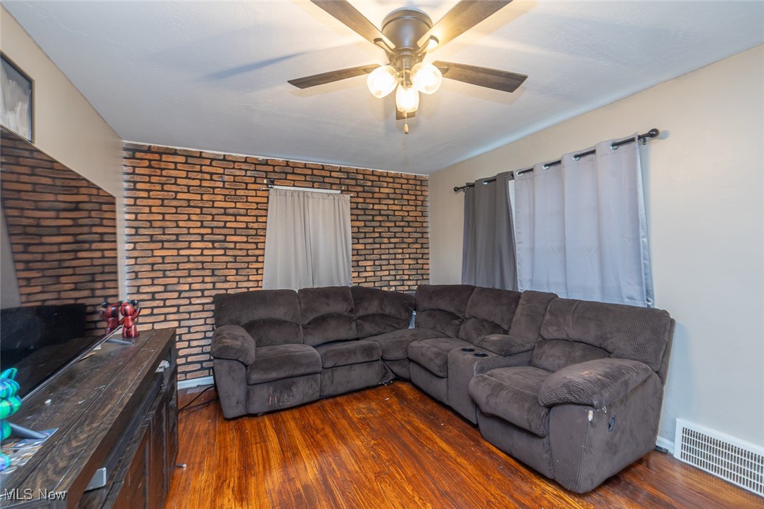21202 Franklin Road Maple Heights, OH 44137 - Photo 2 of 28 Living room featuring brick wall, hardwood / wood-style floors, a ceiling fan, and baseboards