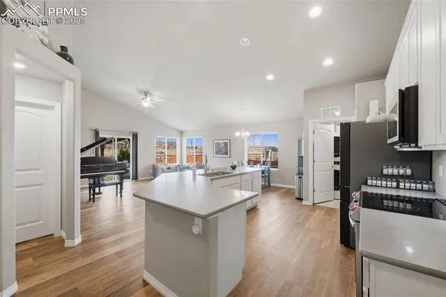 a kitchen with stainless steel appliances granite countertop a refrigerator oven a sink dishwasher and a dining table with wooden floor