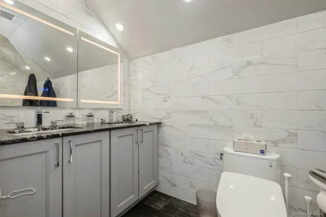 a bathroom with a granite countertop toilet sink and mirror