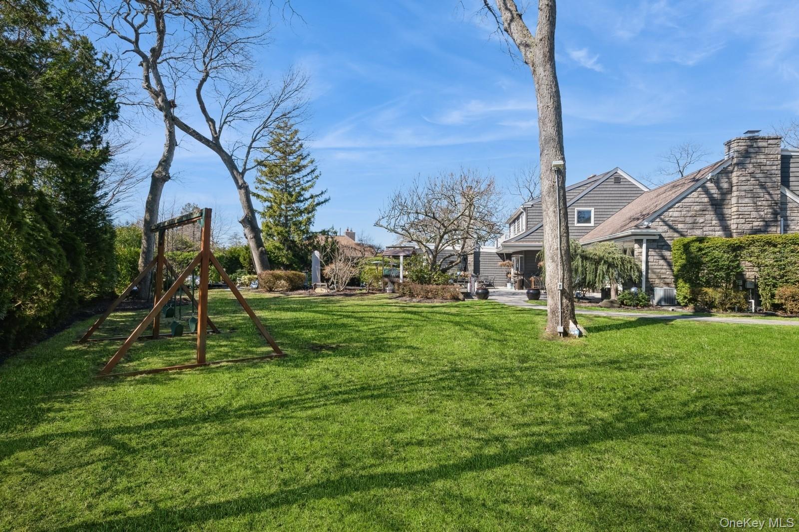 123 Barrett Road Lawrence, NY 11559 - Photo 27 of 32 a view of a backyard with a slide trees and wooden fence