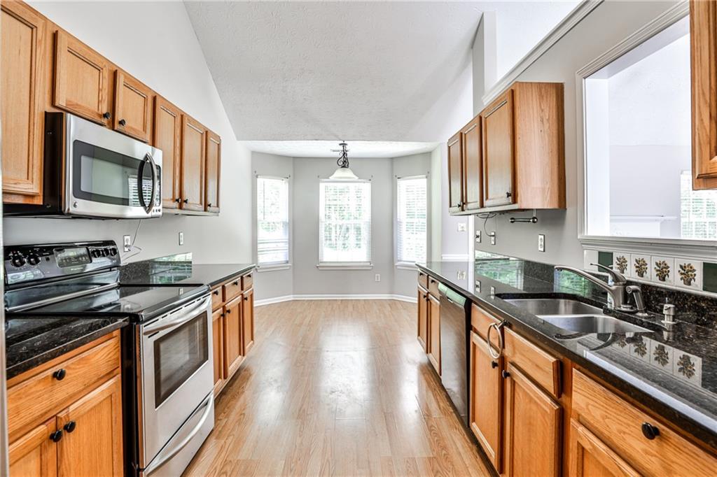 1505 Heatherton Road Dacula, GA 30019 - Photo 11 of 33 a kitchen with stainless steel appliances granite countertop a stove a sink and a microwave