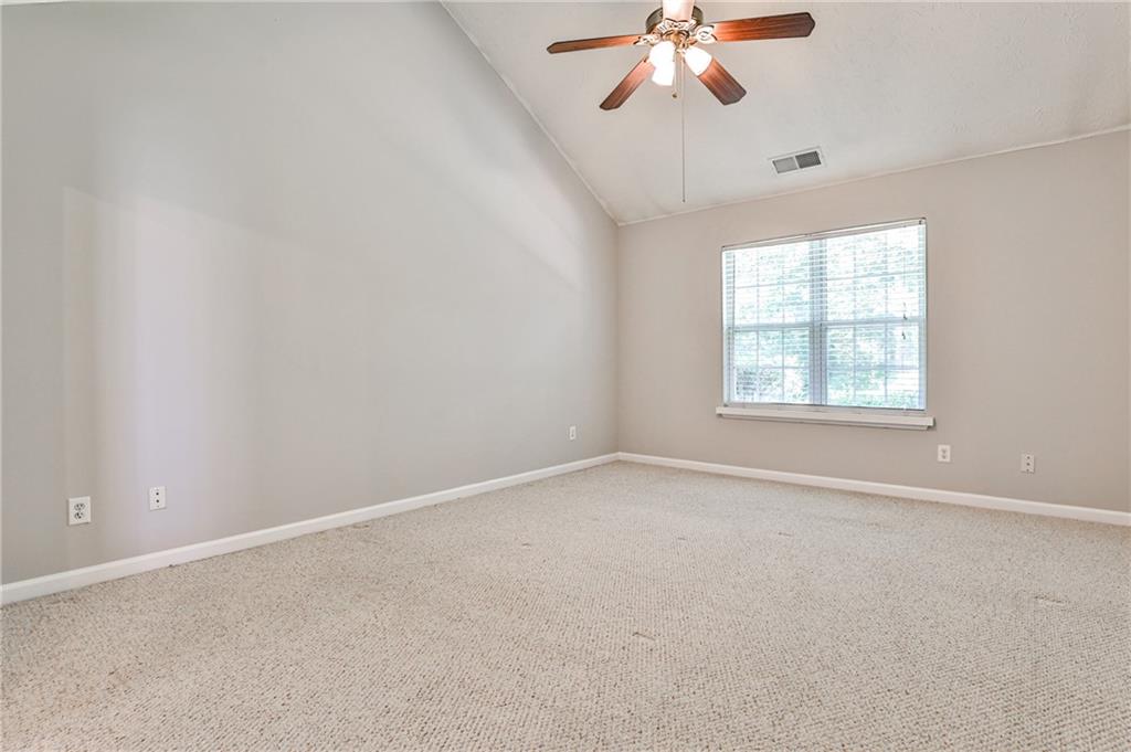 1505 Heatherton Road Dacula, GA 30019 - Photo 15 of 33 an empty room with a chandelier fan and windows