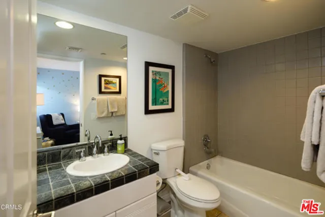 a bathroom with a granite countertop sink toilet a mirror and shower