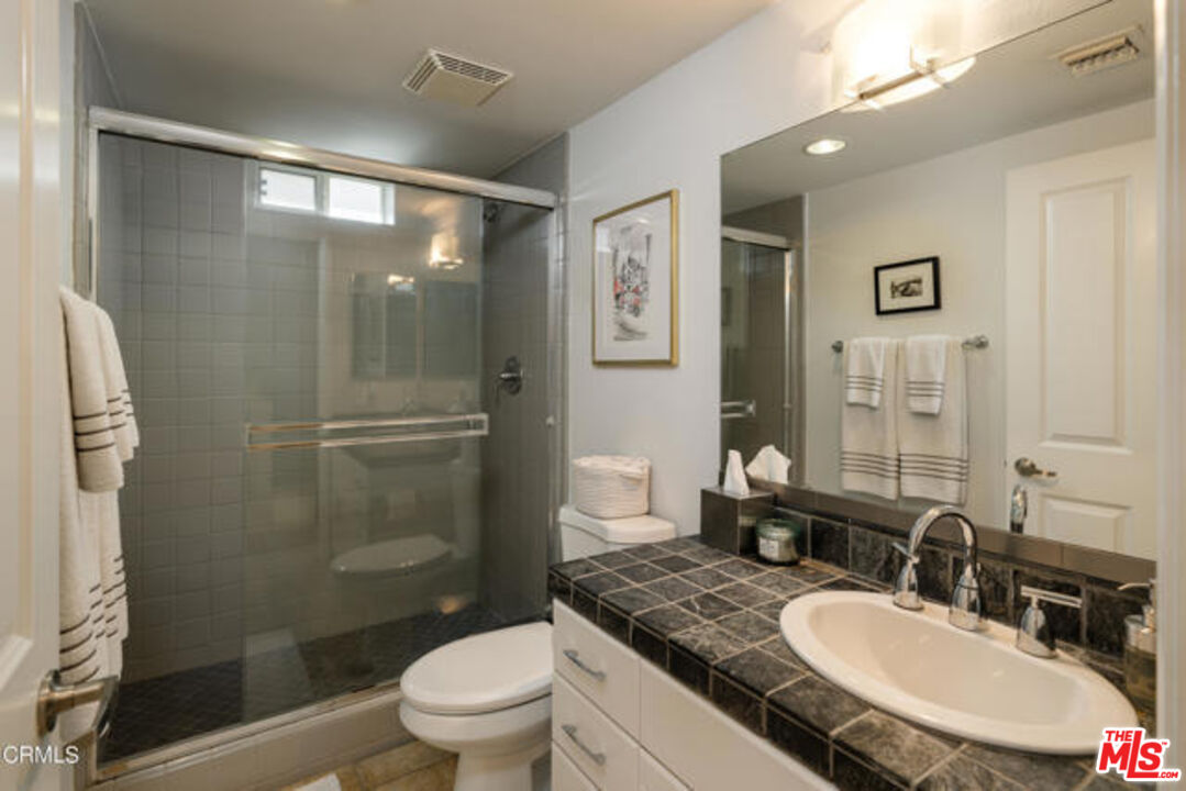 10918 Morrison Street, Unit 12 North Hollywood, CA 91601 - Photo 21 of 28 a bathroom with a granite countertop sink toilet a mirror and shower