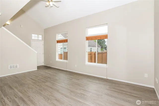 an empty room with wooden floor and windows