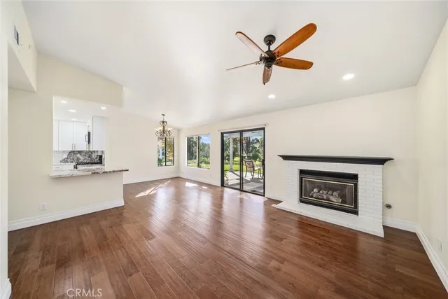 a view of an empty room with a fireplace and wooden floor