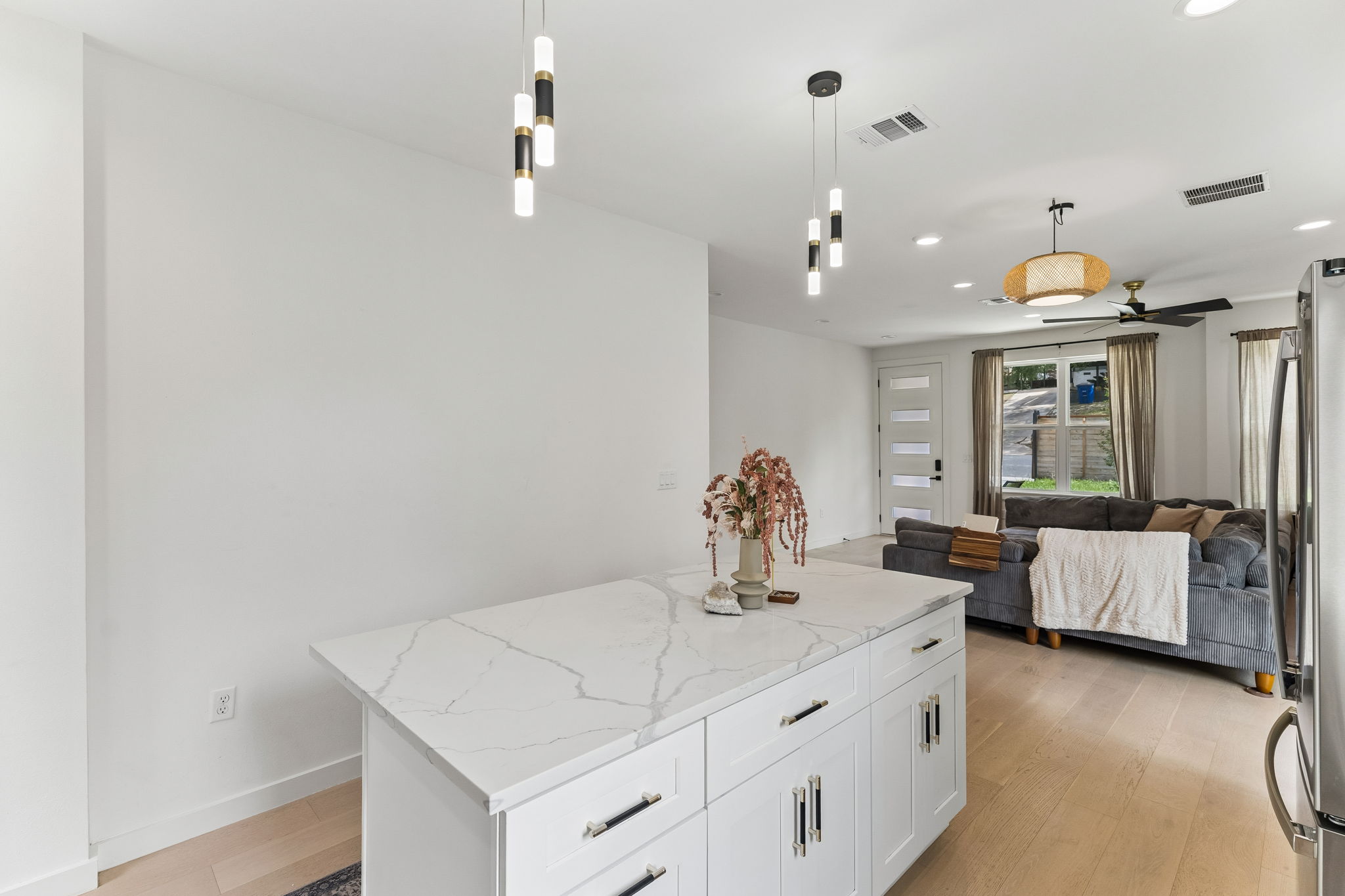 5305 Ledesma Road, Unit 1 Austin, TX 78721 - Photo 10 of 26 A clean, minimalist view of the kitchen island against a crisp white wall, looking toward the entryway. This shot highlights the modern lighting fixtures and the consistent, high-quality finishes found throughout the home.