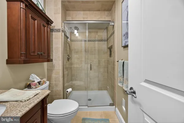 a bathroom with a granite countertop sink a toilet and shower