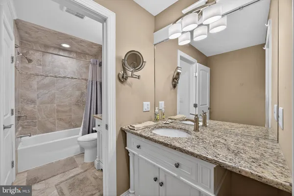 a bathroom with a granite countertop sink a toilet and shower