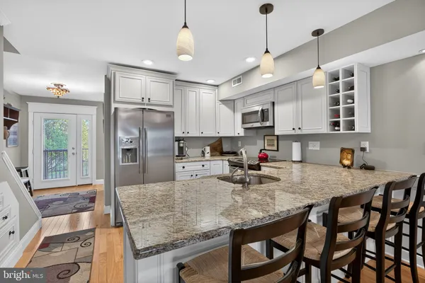 a kitchen with stainless steel appliances granite countertop a stove refrigerator a sink a dining table and chairs
