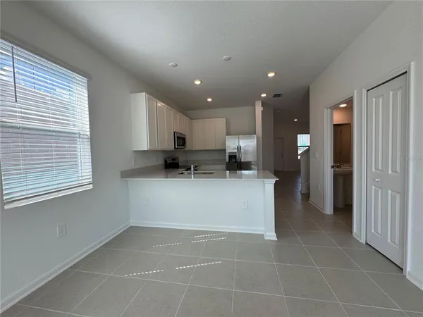 a view of a kitchen with kitchen island stainless steel appliances refrigerator sink and cabinets