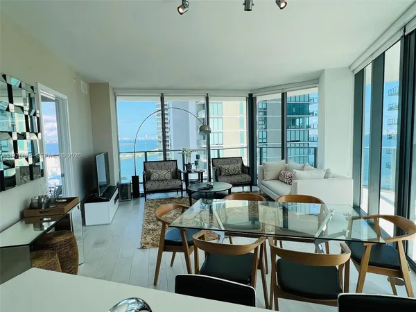 a living room with furniture floor to ceiling window and wooden floor