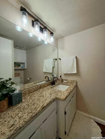 a bathroom with a granite countertop sink a toilet and a mirror