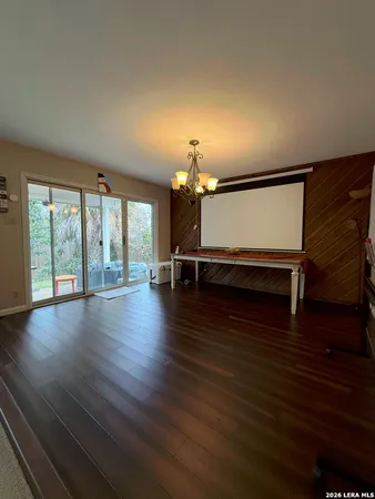 a view of a room with wooden floor chandelier and windows