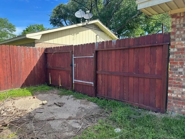 a small barn with a small yard and wooden fence