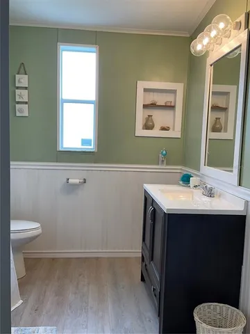a bathroom with a sink a toilet a mirror and a window