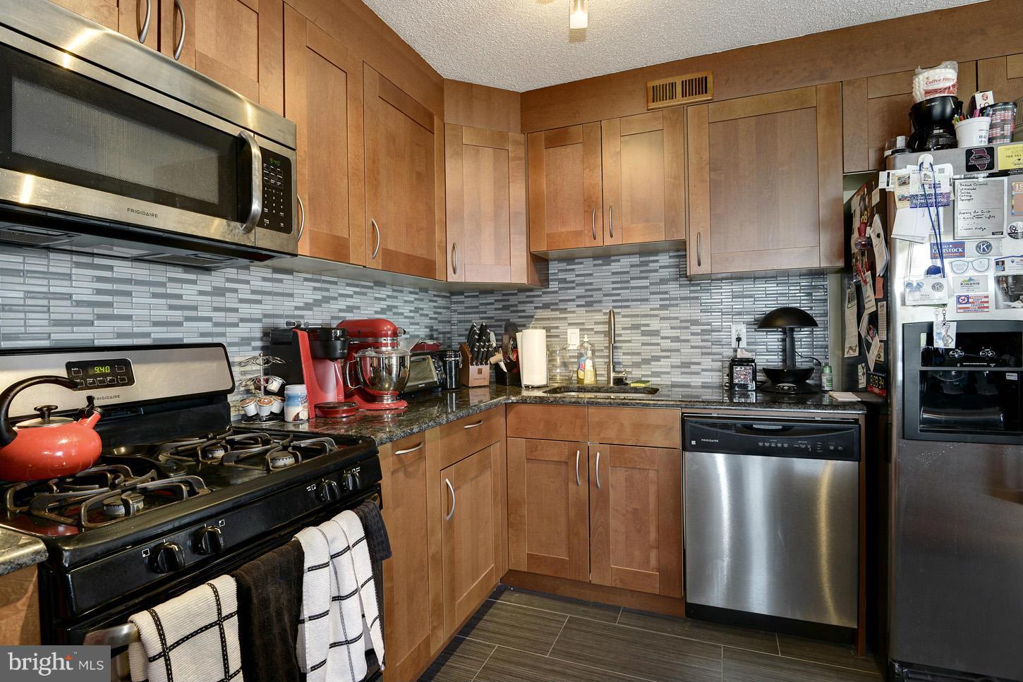 1250 4th Street Southwest, Unit W614 Washington, DC 20024 - Photo 9 of 22 a kitchen with stainless steel appliances a stove a sink and wooden cabinets