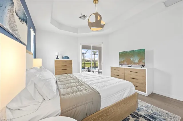 a bedroom with a large bed and a flat tv screen on dresser