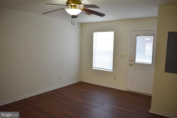 a view of an empty room with wooden floor and a window