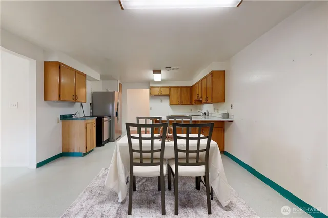 a kitchen with stainless steel appliances kitchen island granite countertop a dining table chairs and a refrigerator