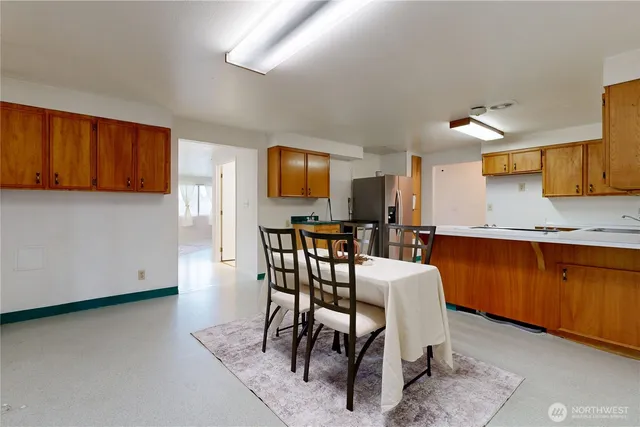 a open kitchen with stainless steel appliances granite countertop a stove top oven a sink a dining table and chairs with wooden floor