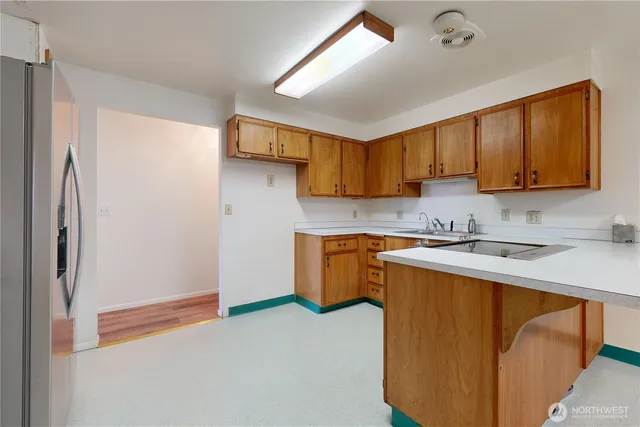 a kitchen with stainless steel appliances granite countertop a refrigerator a sink dishwasher a stove with wooden cabinets