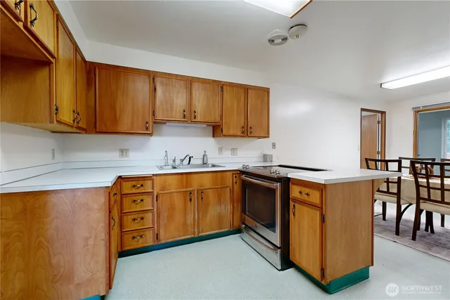 a kitchen with stainless steel appliances granite countertop a stove a sink dishwasher and a refrigerator with wooden cabinets