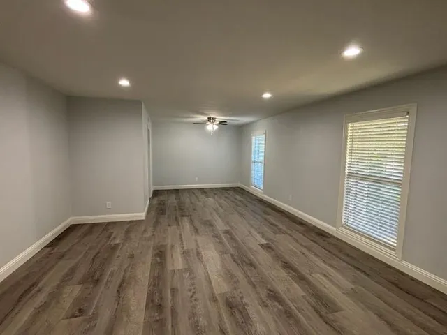 an empty room with wooden floor and windows