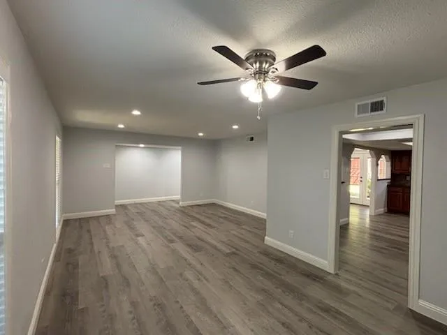 a view of an empty room with wooden floor and a ceiling fan