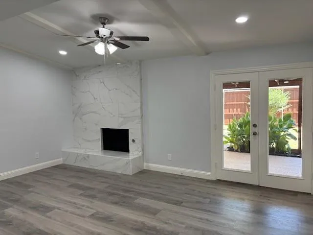 an empty room with wooden floor fan and windows