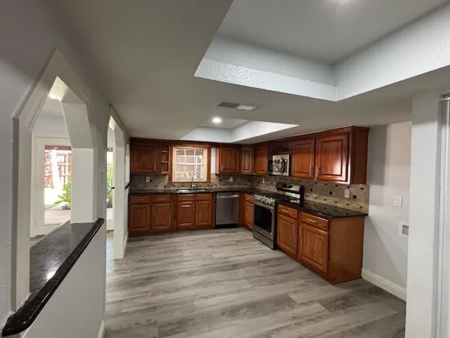 a large kitchen with stainless steel appliances wooden cabinets and a stove top oven