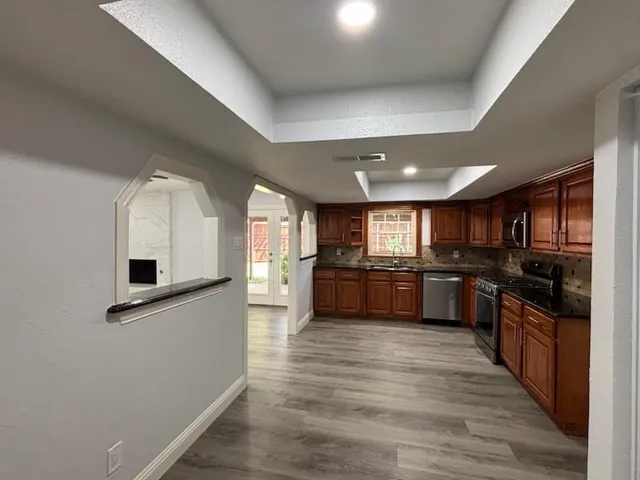 a kitchen with stainless steel appliances kitchen island granite countertop a stove a sink and a refrigerator