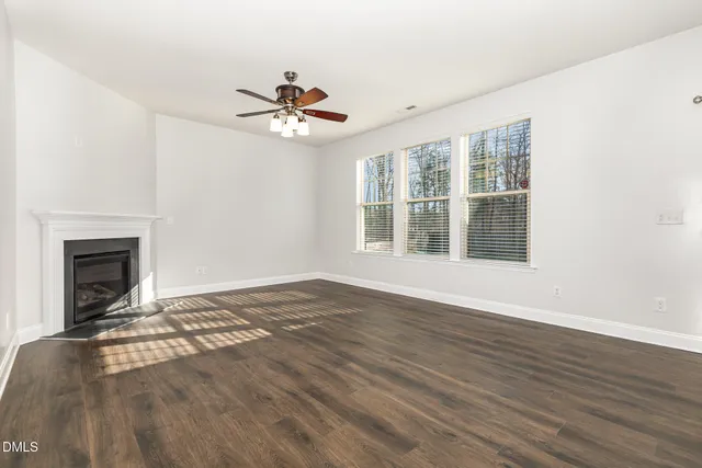 a view of kitchen and empty room with wooden floor